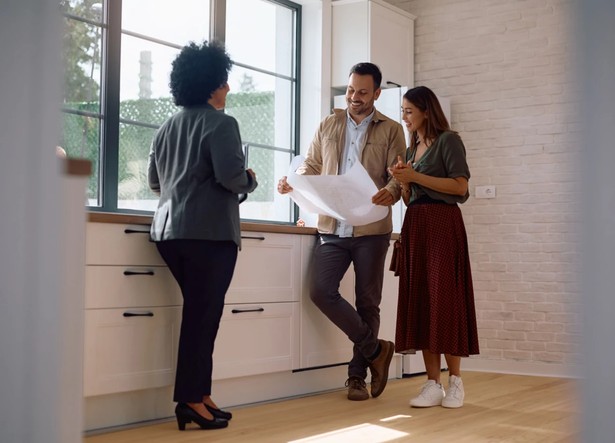 Realtor showing couple house plans in kitchen.