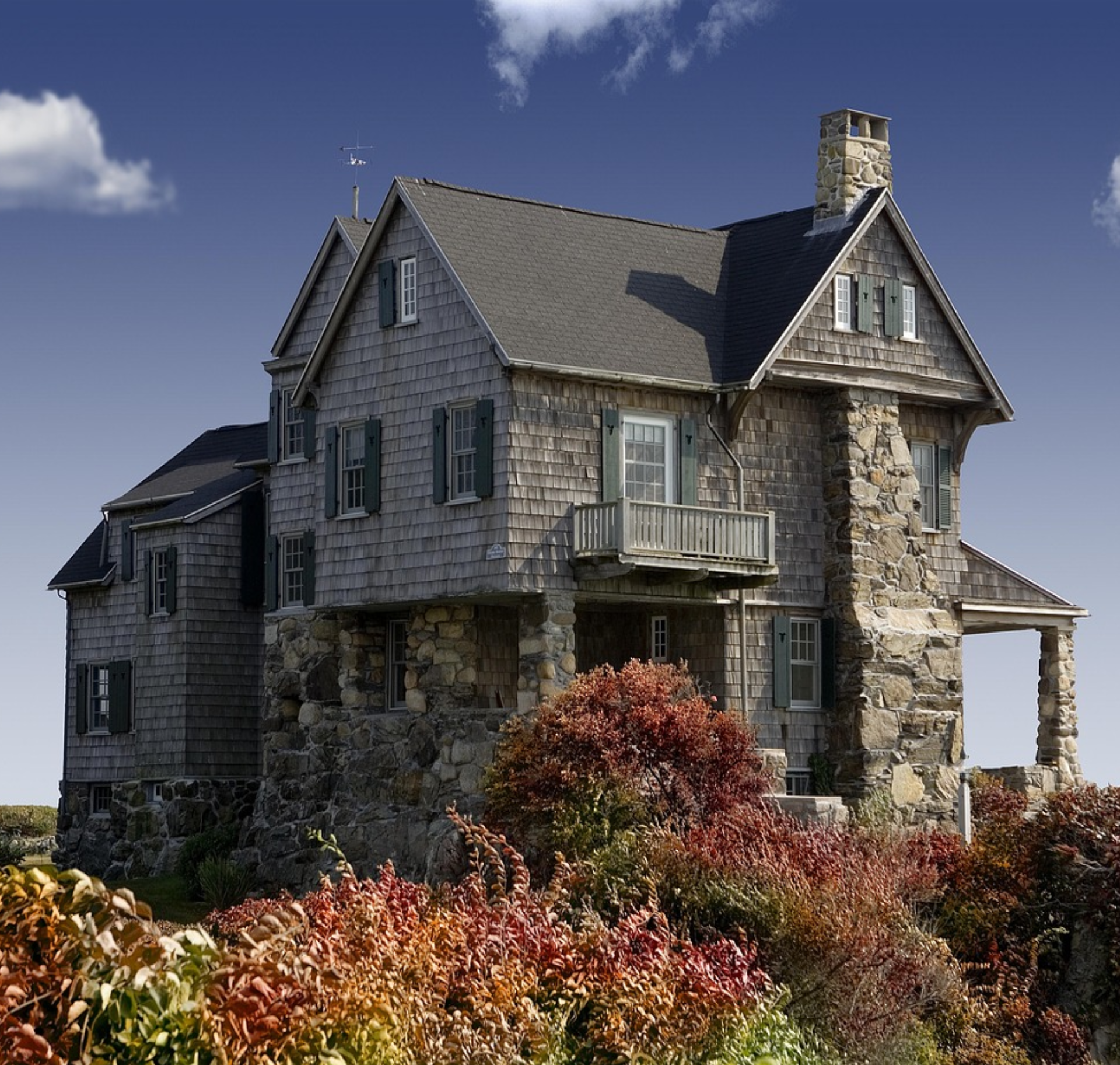 Stone house with autumn foliage and blue sky.